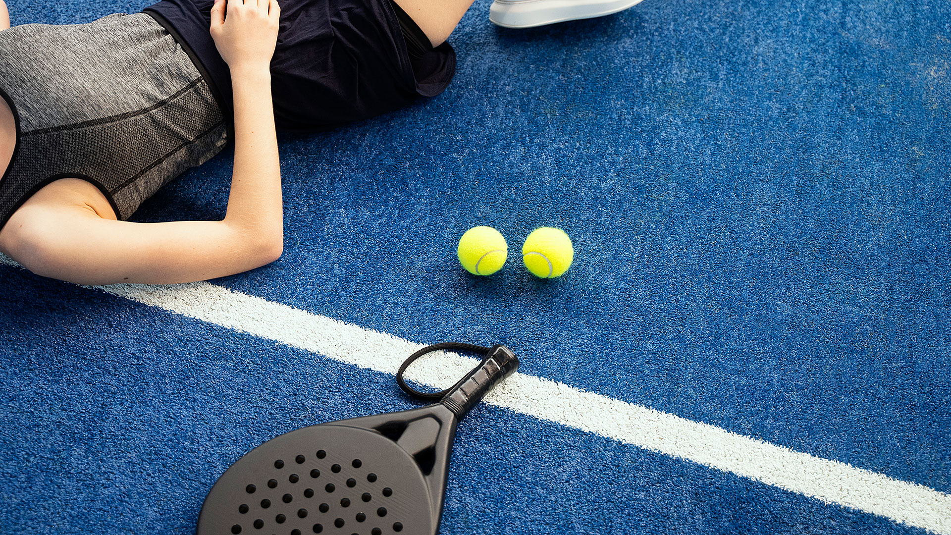 Kvinde der ligger på en padel bane